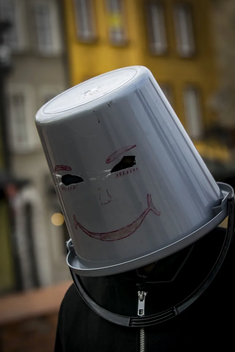 Person wearing a white bucket with a smiley face drawn on it